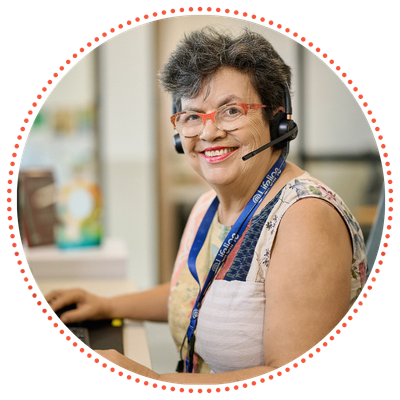 A Crisis Supporter wearing a headset and glasses smiles while looking at a computer screen.